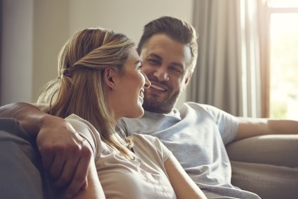 mlada rodina Pojištěný a šťastný mladý pár sedí v objetí na sedačce