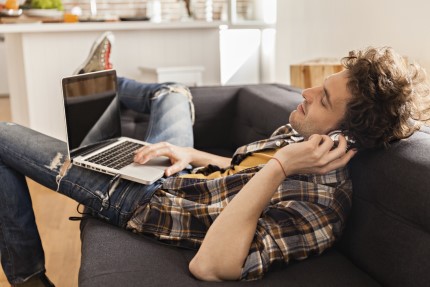 student Pojištěný student leží na pohovce a poslouchá hudbu
