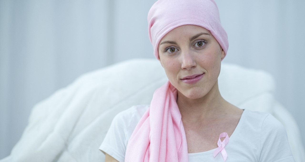 Mladá žena srývá ztrátu vlasů po léčbě rakoviny růžovým šátkem.
